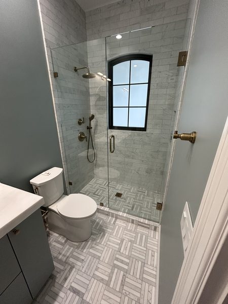 Finished marble walk-in shower with brass fixtures in a Pinellas County bathroom remodel