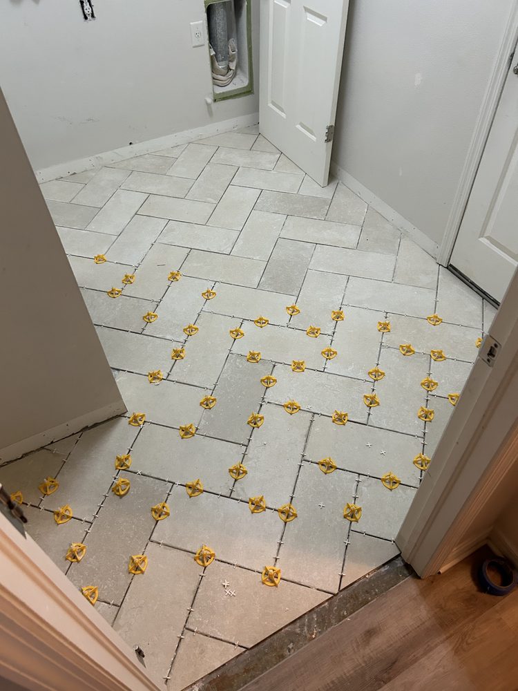 Tile leveling clips holding herringbone floor tile flat while the mortar cures